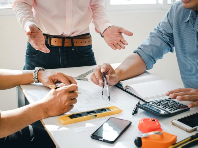 Engineer and contractor planning projects together at desk with