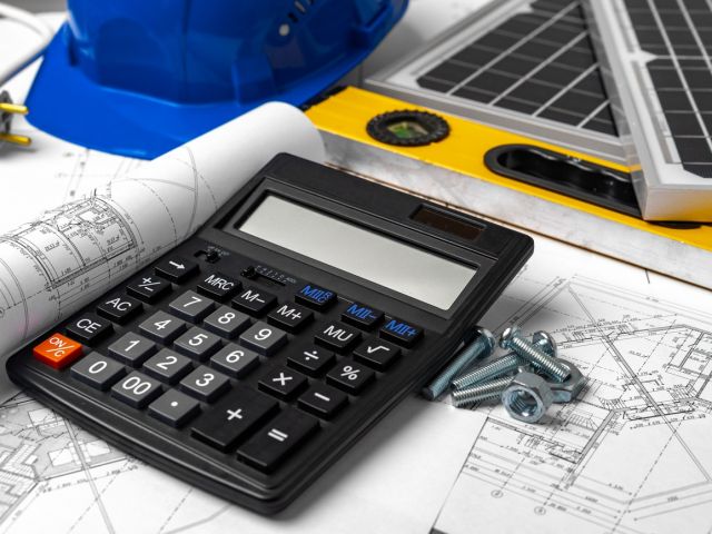 Construction blueprints, hardhat and solar battery on architect's table